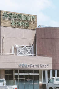 施設の建物外観。看板が掲げられた3階建ての建物で、駐車場も見える。