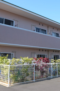 鉄骨造の介護施設建物の外観。複数階と手すり付きのバルコニーが見える。