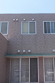 赤レンガ造りの介護施設の建物外観。2階建てで窓が規則的に配置されている。